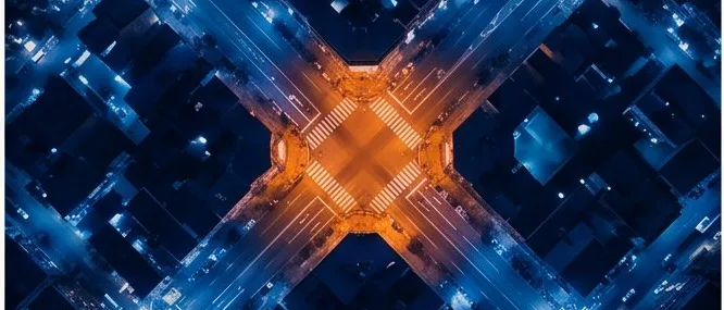 Aerial view of a city street grid at night, one intersection lit orange